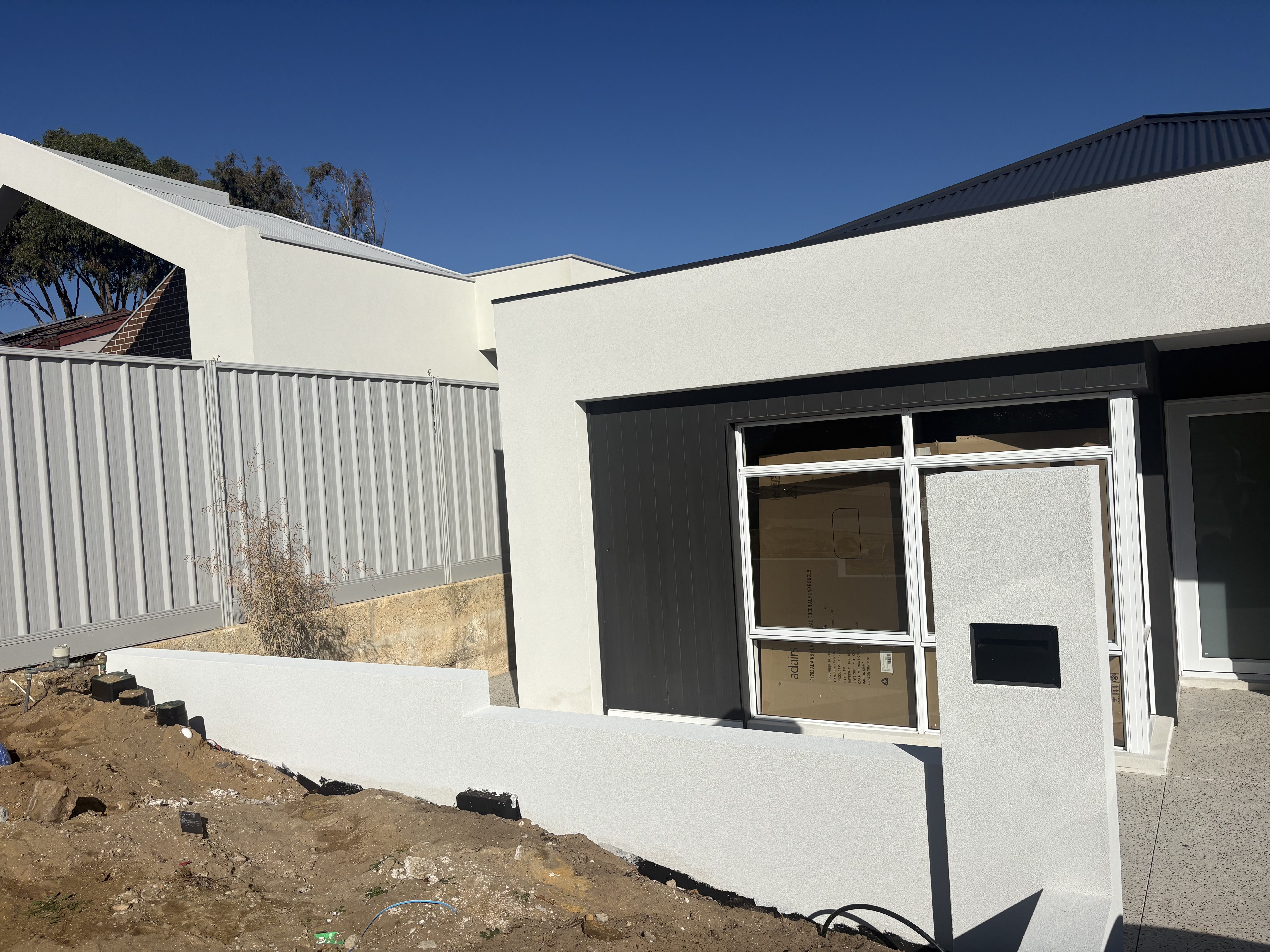 Completed full exterior cement render on a modern Perth home with landscaped front garden